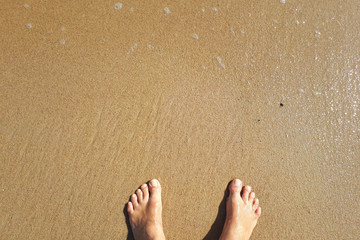 feet on coastal sand by the ocean