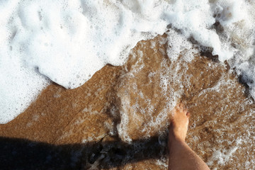 feet in sea foam on the ocean