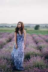 Fototapeta na wymiar beautiful girl in a long dress walking in a lavender field at sunset. Soft focus.