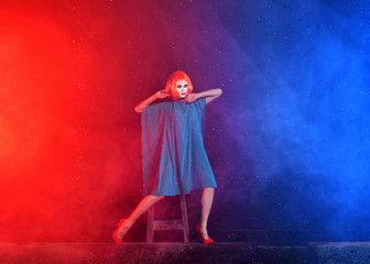 mystical girl with red hair in a white mask on a blue background with smoke