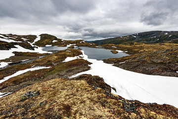 Typical norwegian landscape with snowy mountains and clear lake near the famous Aurlandsvegen (Bjorgavegen), mountain road, Aurland, Norway.