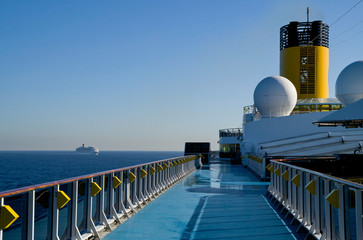 Passengers stroll on deck of Italian Costa Cruises cruiseship or cruise ship liner at sea with blue...
