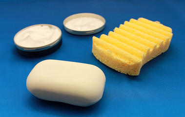 Natural face cream, toilet soap and body washcloth on a blue background