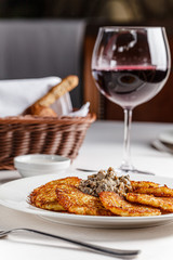 Ukrainian cuisine. A grated potato dish of deruny, draniki grated on a white plate with red wine. Serving dishes in a restaurant in a white plate. background image, copy space text