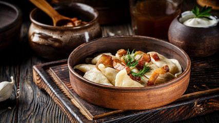 Ukrainian cuisine. vareniki with potatoes and fried pork fat - cracklings. Serving dishes in a Ukrainian style restaurant with sour cream on a wooden background. background image, copy space text