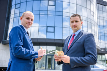 Two men in suit making deal outdoors
