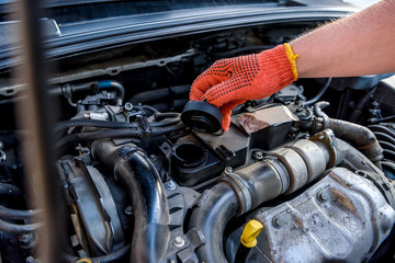 Hands of mechanic's in protective gloves with car engine close up