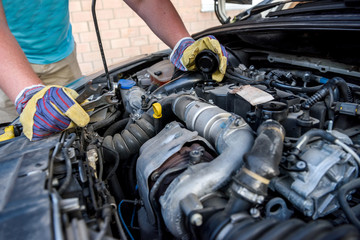 Hands of mechanic's in protective gloves with car engine close up