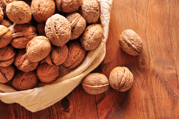 Whole walnuts on rustic old wooden table, walnuts in a reusable cloth bag