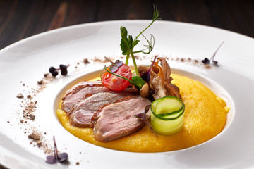 Corn porridge with meat and mushrooms, on a white plate. polenta, ugali, Banosh, mamaliga