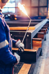 Worker operating acetylene torch in big factory.