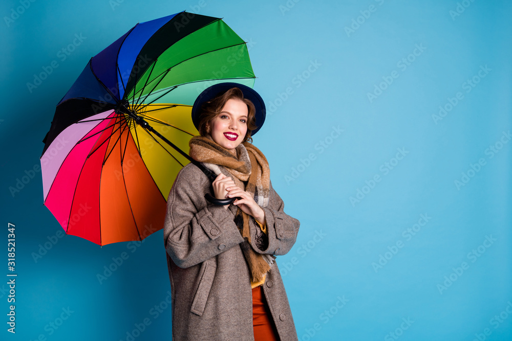 Sticker Rain will not stop me. Photo of pretty traveler lady hold colorful parasol walking down street wear stylish casual long grey coat jumper pants hat scarf isolated blue color background