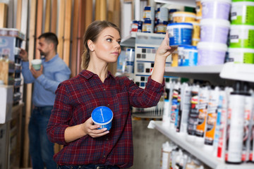 Woman is choosing with paint for repair