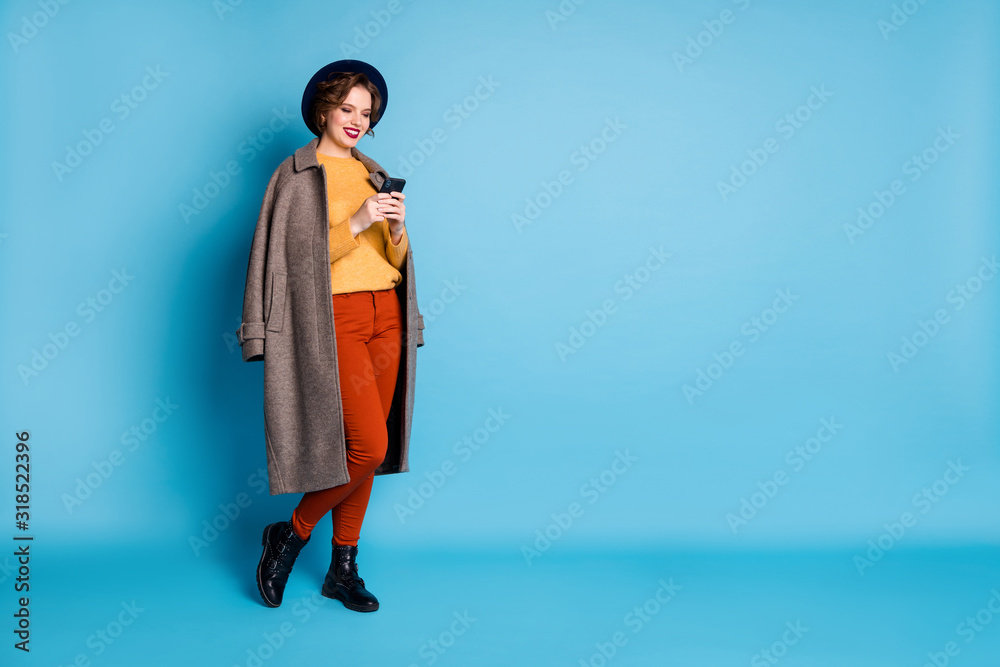 Sticker Full body photo of pretty lady traveler abroad search telephone nearest shopping center wear casual long grey coat pullover trousers hat shoes isolated blue color background