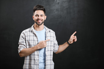 Male student pointing at blackboard in classroom