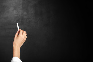 Female teacher writing on blackboard in classroom