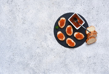 Toast bread with red caviar. Sandwich with caviar and butter on a concrete background.