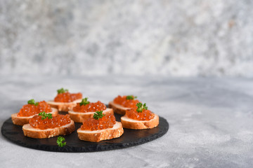 Toast bread with red caviar. Sandwich with caviar and butter on a concrete background.