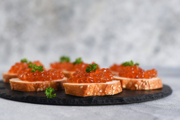 Toast bread with red caviar. Sandwich with caviar and butter on a concrete background.