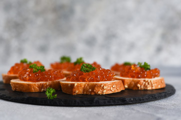 Toast bread with red caviar. Sandwich with caviar and butter on a concrete background.