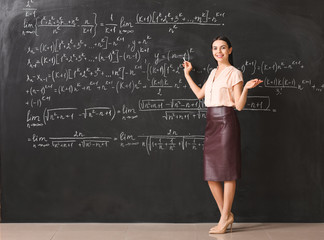 Female teacher near blackboard in classroom