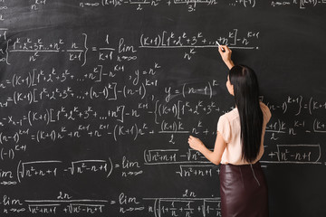 Female teacher writing on blackboard in classroom