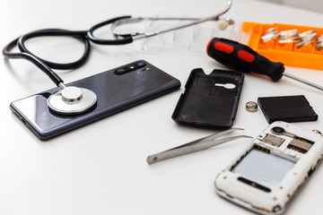 Stethoscope on the smartphone on a grey background. Phone repair and service concept. Concept a health of device.