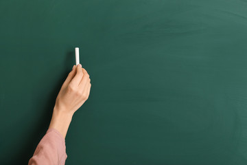 Naklejka premium Female teacher writing on blackboard in classroom