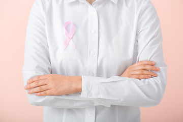 Young woman with pink ribbon on color background, closeup. Cancer awareness concept