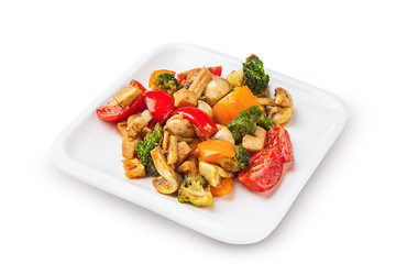 Healthy vegetarian cuisine with a tofu salad with colorful roast vegetables including sweet peppers, onion and mushrooms, peas and broccoli.