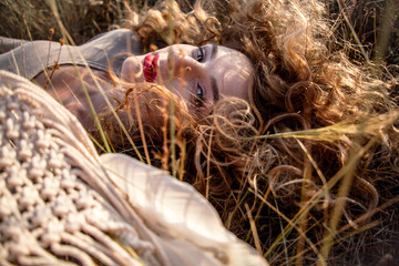 Portrait of the beautiful pregnant woman sit on the field against the sunset and holding the dreamcatcher. Model is in harmony with nature, expecting the baby.