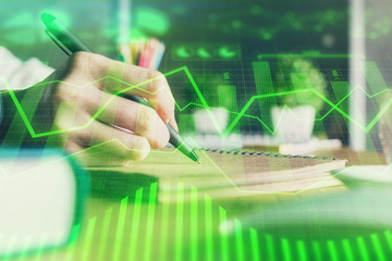 Financial forex charts displayed on woman's hand taking notes background. Concept of research. Double exposure