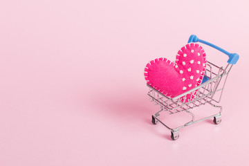 Red heart as a symbol of love, in a shopping trolley, the concept of buying heart for money for Valentine's Day. Commercial promotion, copy space.