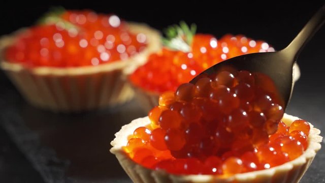 Woman puts red caviar in a tartlet