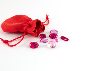 Gemstones and red pouch for them isolated on white background