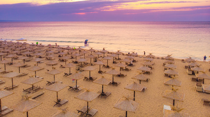 Aerial top view on the sandy beach. Umbrellas, sand and sea waves landscape.