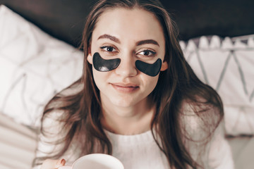 in the morning in bed the girl pasted black patches under her eyes