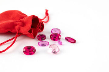 Gemstones and red pouch for them isolated on white background