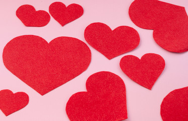 Red felt hearts on a pink background. Valentines Day greeting card and romance concept. Top view, flat lay, copy space.