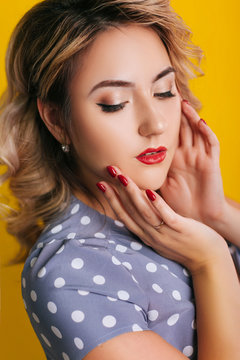 Girl with red lips and a dress in peas on a yellow background. Pin-up Portraits