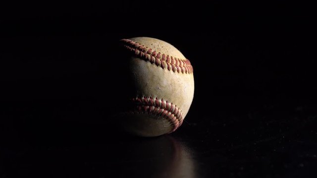 A baseball spinning on a black background. 4K