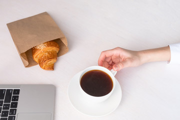 Obraz na płótnie Canvas White cup with coffee in hand on a white background and fresh croissant