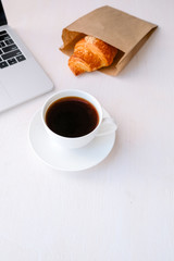 Cup of coffee from a laptop computer with fresh croissants. on white background.concept of education