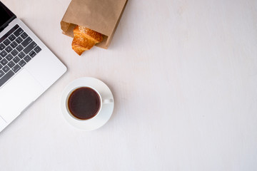 Cup of coffee from a laptop computer with fresh croissants. on white background.concept of education