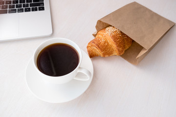 Cup of coffee from a laptop computer with fresh croissants. on white background.concept of education