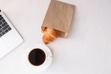 Cup of coffee from a laptop computer with fresh croissants. on white background.concept of education
