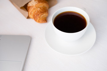 Cup of coffee from a laptop computer with fresh croissants. on white background.concept of education
