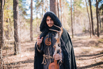 A man with a beard and a mustache in a robe and coat with a staff in his hand. A magician, a shaman...