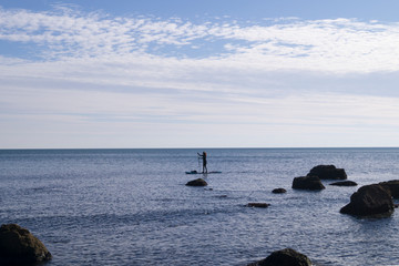 girl on a sap board is swimming in the sea