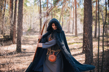 A man with a beard and a mustache in a robe and coat with a staff in his hand. A magician, a shaman...